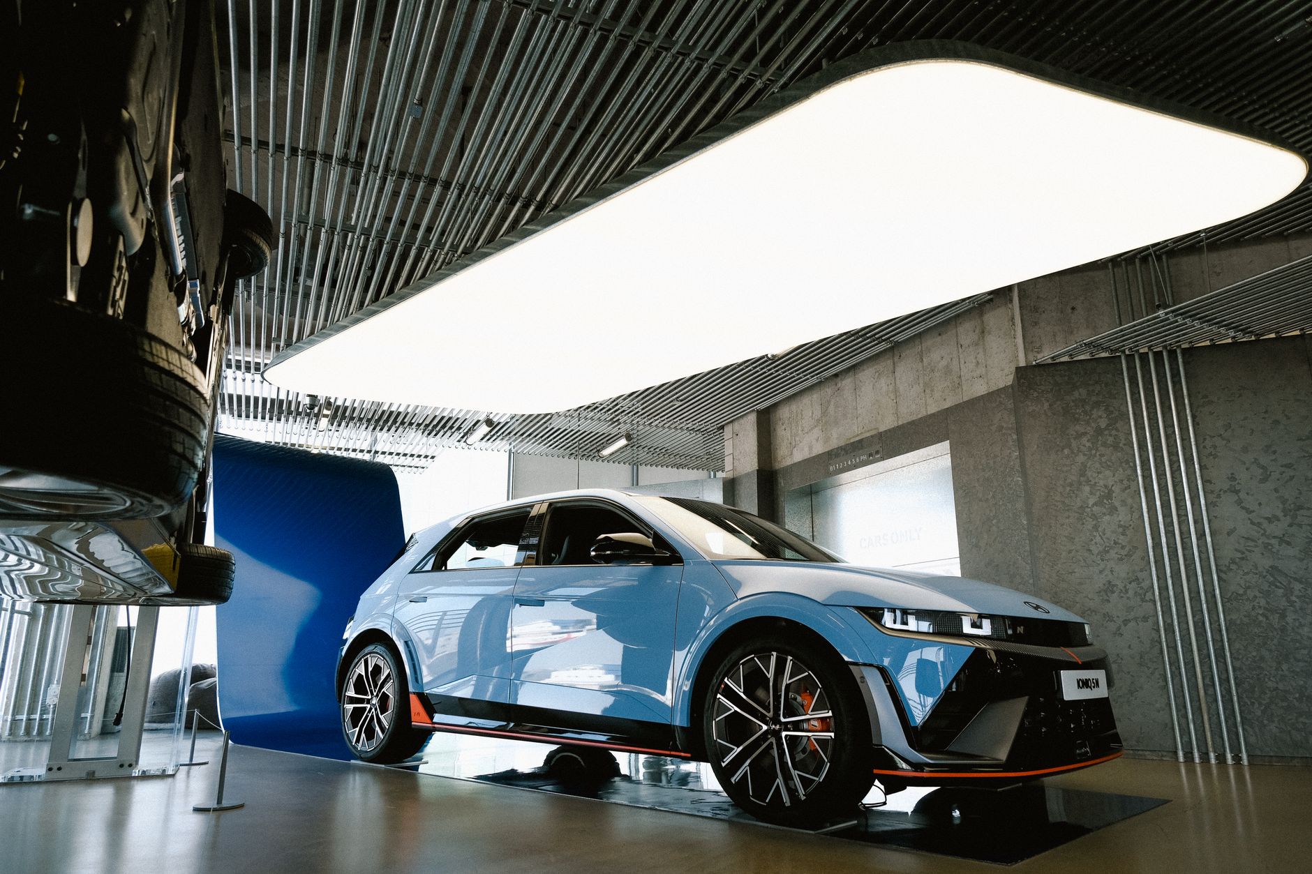 Salesman with PCP deal paperwork next to a hot hatch in a UK car showroom